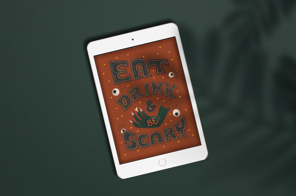 ipad laying on a dark green background, featuring custom artwork that says "eat, drink, and be scary" with eyeballs and a zombie hand